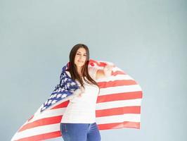 mulher jovem e bonita com bandeira americana sobre fundo azul foto