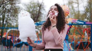 garota sorridente e animada segurando algodão doce no parque de diversões foto