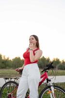 menina com sua bicicleta ouvindo música no parque ao pôr do sol foto