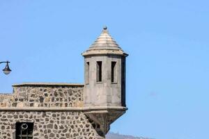 uma pedra torre com uma relógio em topo foto