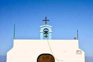 uma branco Igreja com uma Sino e Cruz em topo foto