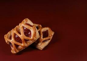 sopro pastelaria pastelaria com amora silvestre geléia em uma Sombrio vermelho fundo. biscoitos com amora silvestre geléia. foto