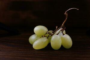 pequeno grupo do maduro verde uvas em uma de madeira fundo. foto