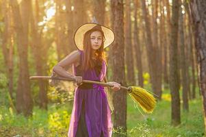 jovem com uma fantasia de halloween na floresta com uma vassoura. foto