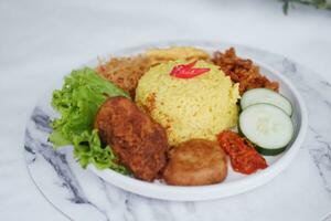 indonésio estilo amarelo arroz com frango e lado pratos dentro branco prato foto