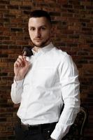 elegante jovem empresário de camisa branca segurando uma jaqueta no dedo foto