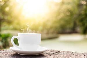 xícara de café branca em cima da mesa de madeira com fundo desfocado foto