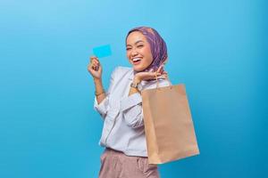 retrato de uma mulher alegre segurando sacolas de compras e cartão de crédito foto