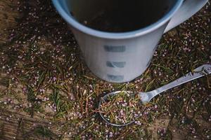 xícara e colher com chá de flores em um fundo de madeira foto