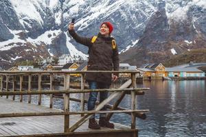 homem tirando uma selfie com montanhas e lago atrás dele foto