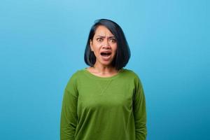 mulher asiática chocada com a boca aberta em fundo azul foto