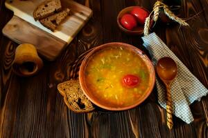 tomate sopa dentro uma argila prato em uma de madeira vintage Fazenda mesa perto uma peça do Castanho pão. foto