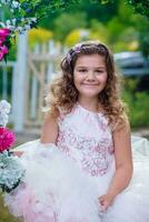 emocional pequeno menina dentro vestir posando com flores foto