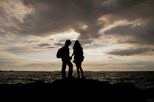 silhueta do casal em pé em a de praia às pôr do sol foto