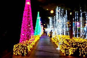 borrado e bokeh do Natal feriado iluminação com pessoas em noite Tempo fundo. foto