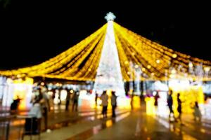 borrado e bokeh do Natal feriado iluminação com pessoas em noite Tempo fundo. foto