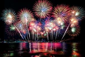 incríveis e lindos fogos de artifício coloridos na noite de celebração, mostrando na praia do mar com reflexo de várias cores na água foto