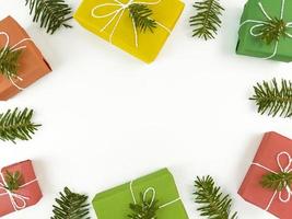postal de férias com galhos de pinheiros e caixas de presente em um branco foto