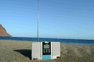 uma rádio sentado em a areia perto a oceano foto