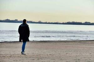 homem caminhando na praia foto