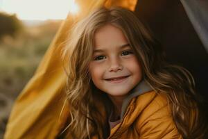 retrato do fofa pequeno menina às Câmera enquanto em pé perto acampamento barraca às pôr do sol ai gerado foto