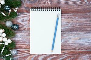 Natal composição com em branco bloco de anotações, lápis para desejo Lista e Natal decoração em de madeira fundo. flatlay. topo visualizar. cópia de espaço. foto