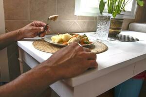 uma homem comendo uma vegetal prato com carne, dentro uma moderno e brilhante cozinha, decorado com plantas. estilo de vida conceito. foto