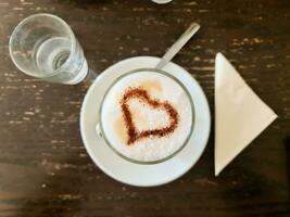 uma saboroso café com leite e uma coração do chocolate em isto foto