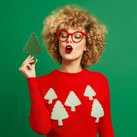 engraçado encaracolado senhora dentro uma vermelho suéter, segurando uma pequeno, brilhante verde Natal árvore decoração - ai generativo foto