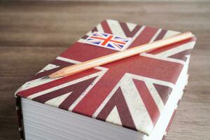 Inglês livro com graduado chapéu, Aprendendo e tutorial para estrangeiro. foto