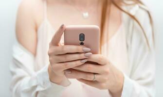 fêmea mãos jovem mulher usando Rosa caso inteligente telefone foto