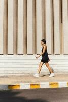 mulher exercício caminhando em a rua mão segurando garrafa água. foto