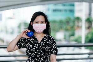 ásia mulher vestindo mascarar e segurando azul coração em mão para proteger coronavírus ou covid-19 conceito. foto