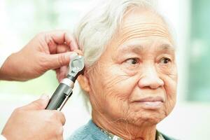 otorrinolaringologista ou ent médico médico examinando Senior paciente orelha com otoscópio, audição perda problema. foto