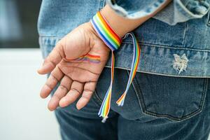 senhora asiática usando pulseiras de bandeira do arco-íris, símbolo do mês do orgulho LGBT, comemora anual em junho social de gays, lésbicas, bissexuais, transgêneros, direitos humanos. foto