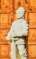uma estátua do uma cavaleiro em pé dentro frente do uma de madeira porta foto