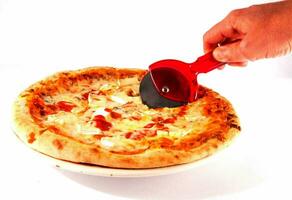 uma pessoa é usando uma pizza cortador para cortar uma pizza foto