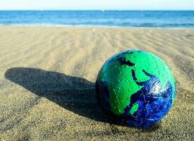 uma verde e azul globo em a areia foto