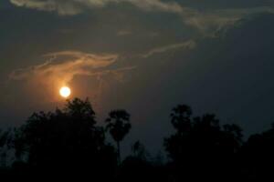 o sol nasce e se põe de manhã e à noite e as árvores estão sombreadas em preto - céu laranja e nuvens. quente, romântico e gloriosamente bonito, parece quente e viaja. foto