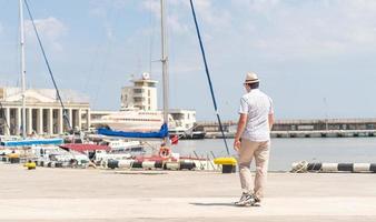 turista caminhando no porto marítimo, barcos e iates ao fundo foto