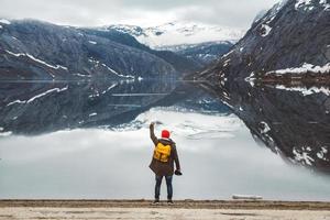 homem parado no fundo das montanhas e do lago tira uma foto