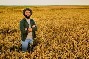 retrato do agricultor quem é cultivar trigo. ele é satisfeito com Boa progresso do plantas. agrícola ocupação. foto