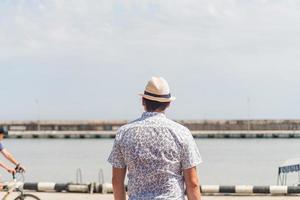 homem olhando para o mar, parado no porto foto