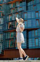 mulher com vestido de verão e chapéu em frente a um escritório moderno foto