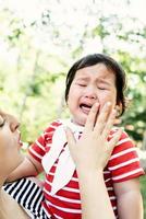 menina asiática chorando nas mãos da mãe