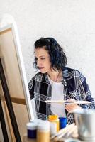 mulher criativa com cabelo tingido de azul pintando em seu estúdio foto