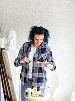 mulher criativa com cabelo tingido de azul pintando em seu estúdio foto