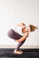 mulher loira praticando ioga em casa