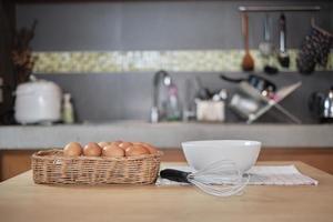fazenda de ovos frescos na cesta de madeira, tigela branca na cozinha de casa. foto