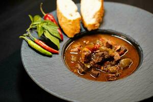 tradicional húngaro Comida carne Goulash com pão a picante pimentas foto